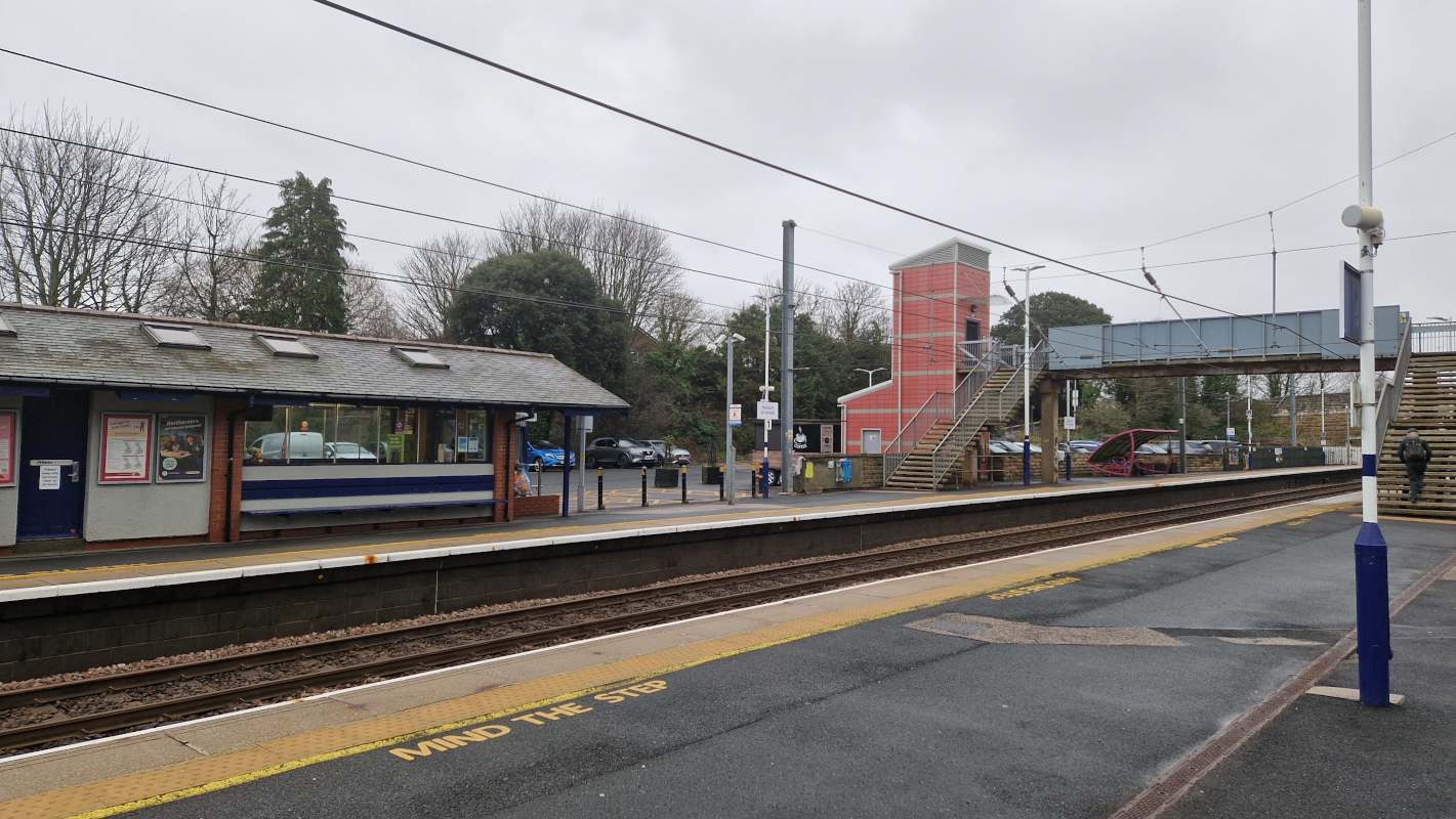 A two-platform railway station with a small ticket hall and a (slightly ugly) platform crossing bridge