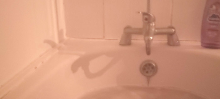 The shadow of a bathtub tap appears to form an OK hand